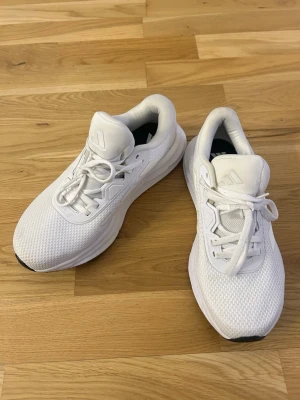 Vita Adidas sneakers med mesh - Snygga helvita sneakers från Adidas med mesh-ovandel och Ortholite-innersula för extra komfort. Klassisk låg modell med vita snören och diskret Adidas-logga på plösen. 