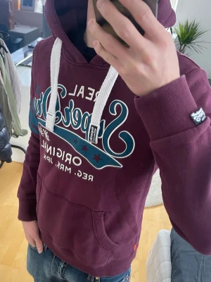 Vinröd Vintage 2000s Superdry Hoodie (Limited edition)) - Säljer nu denna sjukt snygga och sällsynt vintage 2000s Superdry Hoodie! Sjukt snygg vinröd färg och perfekt passform😊 Hoodien är ur en limiterad upplaga med endast ca 700 sålda 🙌 Både mjuk och bekväm och passar perfekt nu mot våren🤝 Passar storlek XS eller en liten 🤩 Skriv vid funderingar 📲