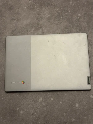 Lenovo Chromebook bärbar dator - Lenovo Chromebook med stilren design i ljusgrå färg och matta material. Datorn har en stor skärm, svart tangentbord och bred touchpad. Perfekt för surf, studier och streaming. Logotypen syns tydligt på locket och den har en modern look.