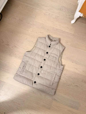 Beige Stenströms vest ÄKTAA!! - Säljer en stilren beige vest från Stenströms med quiltad design och diskret broderad logotyp. Vesten har ett yttre fack och är tillverkad i ett slitstarkt tygmaterial. Perfekt en grisch outfit. Ny pris är 3500. Pris kan diskuteras!