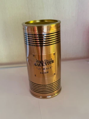 Jean Paul Gaultier Le Male Elixir - Säljer en Jean Paul Gaultier Le Male Elixir parfym i en snygg guldfärgad metallburk med svarta ränder och präglad logga. Förpackningen har en unik cylinderform och känns riktigt lyxig och modern. Perfekt för dig som gillar exklusiva dofter.