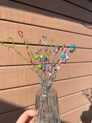 Färgglada pärlblommor i glasvas - Unika handgjorda dekorationer av pärlor i olika färger och former, fästa på böjbara metalltrådar. Perfekt vid fönstret eller på soffbordet. Inslag av hjärtan och pastellfärger ger en lekfull och kreativ känsla. (Vasen ingår ej) 