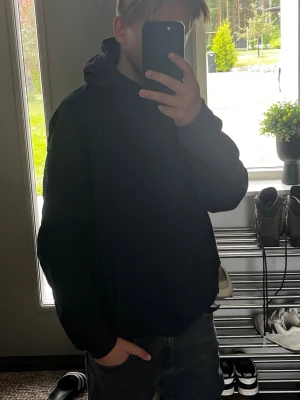 Svart hoodie med magficka - En enkel och stilren svart hoodie med huva och stor magficka framtill. Hoodien har ribbade muddar vid ärmslut och nederkant. Perfekt för dig som gillar en clean och avslappnad look. Materialet känns mjukt och bekvämt mot huden. Modell: 160cm. Vid frågor hör av er för minsta lilla priset kan alltid diskuteras.