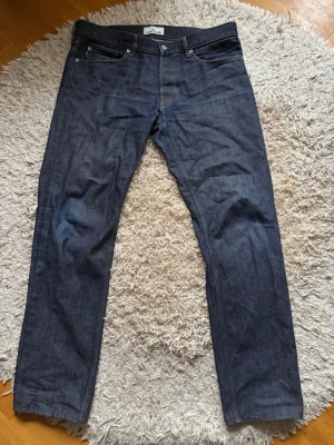 Mörkblå jeans från Stone Island - Säljer ett par mörkblå jeans från Stone Island med klassisk femficksmodell och raka ben. Jeansen har en snygg patch med logga på bakfickan och är gjorda i slitstark denim. Perfekta för dig som gillar streetwear och vill ha en clean look. Storlek 34/34. Garanterat äkthet.
