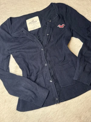 Hollister vintage kofta  - En skitsnygg vintage kofta från Hollister! Senapen väldigt eftertraktad och svår att på tag på. Koftan har spets/fjäderkant på insidan vid knapparna! Skit snygg på och formar fint. Lite kortare ärmar då modellen ska vara så!