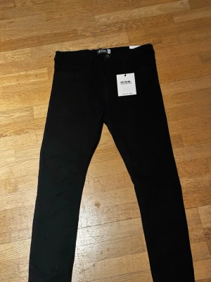Svarta skinny jeans från ICON - Snygga svarta skinny jeans från ICON med klassisk femficksdesign och hög midja. Jeansen har en smal passform och är tillverkade i ett stretchigt material för extra komfort. Perfekta för dig som gillar en stilren och modern look.