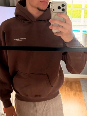 Brun hoodie från Worst Behavior - Säljer en brun hoodie från Worst Behavior med vit text på bröstet och ryggen. Hoodien har stor huva och en klassisk magficka framtill. 