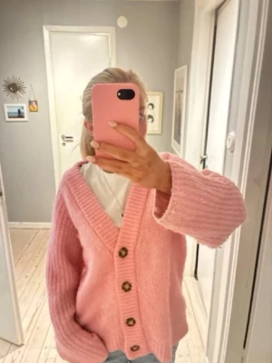 Rosa stickad kofta med knappar - Mysig rosa stickad kofta med stora bruna knappar och bred ribbad kant. Koftan har en avslappnad passform, V-ringning och långa ärmar. Perfekt för lager på lager och ger en söt touch till din outfit. Från zara storlek s💓💓