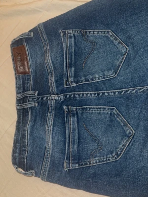 Blå bootcut jeans från ONLY - Säljer ett par snygga blå bootcut jeans från ONLY. Jeansen har snygga detaljer på bakfickorna och är tillverkade i stretchig denim för skön passform. Perfekta och enkla att styla!