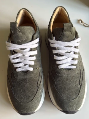Human scales sneakers - Stilrena sneakers i grön mocka med vita skosnören och vit sula. Klassisk låg modell med rund tå och svarta detaljer på yttersulan. Perfekta för en avslappnad och trendig look. Använda 1 gång, pris kan diskuteras
