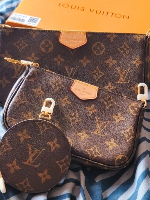 Monogram Multi Pochette  - Stylish monogram multi pouch set in brown coated canvas with gold-tone hardware. Includes a large pouch, small pouch, round coin purse, adjustable pink woven strap, gold chain, dust bag, box and booklet as shown in the photos. Can be worn crossbody, over the shoulder, or the pouches can be used separately. Great everyday bag with plenty of styling options.