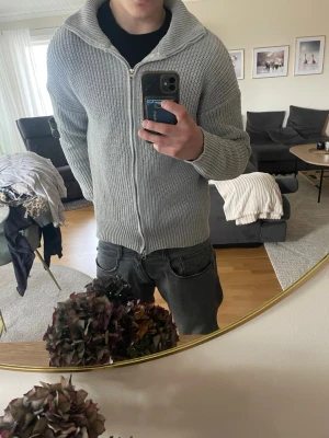 Ljusgrå stickad ziptröja Stone Island - Säljer en ljusgrå stickad ziptröja från Stone Island med hög krage och ribbade muddar. Tröjan har dragkedja framtill och den klassiska Stone Island-loggan på ärmen. Perfekt för dig som gillar stilrena och bekväma plagg. M men passar S också, helt ny oanvänd