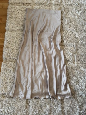 satinlångkjol - Säljer en långkjol i satin med elastisk midja. Kjolen har en mjuk, glansig yta och faller snyggt längs benen. 