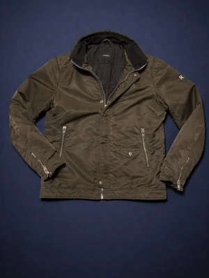 Vindjacka - Snygg mörkgrön vindjacka med hög krage och silverfärgade dragkedjor på fickorna. Jackan är från rockandblue. Väl omhändertagen.