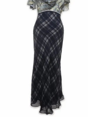 Lång rutig klänning med öppen rygg från Zara strl 34 - Unik långklänning med svart och vit rutig kjol och blommigt mönstrad överdel i gröna toner. Klänningen har korta ärmar, markerad midja och en snygg öppen rygg. Perfekt för dig som vill sticka ut med en mix av mönster och elegant siluett.