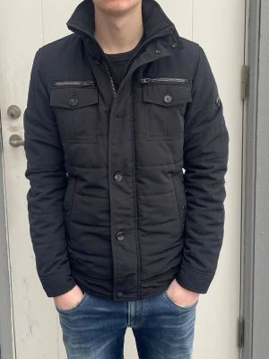 Svart Fieldjacka från J.lindeberg - S - Jag säljer den här riktigt snygga fieldjackan från J.lindeberg i storlek S. Den är inte använd mycket alls och är i fint skick utan skador och defekter. Modellen heter Bailey 56 Structured Poly. Nypris på en sån här låg på 3400kr och jag säljer den för 1499kr. Tveka inte att höra av er!