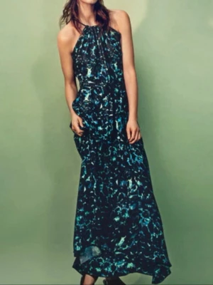 Mönstrad långklänning i blå toner från hm perfekt till sommar - Säljer en snygg långklänning med blått och grönt abstrakt mönster. Klänningen har halterneck och ett luftigt fall som ger en avslappnad men ändå elegant look. Perfekt för sommarkvällar eller när du vill sticka ut lite extra.