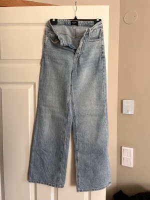 Ljusblåa raka jeans  - Säljer ett par ljusblåa jeans med hög midja och raka, vida ben. Klassisk femficksmodell i ett mjukt denimtyg. Perfekta för dig som gillar en avslappnad och trendig look.