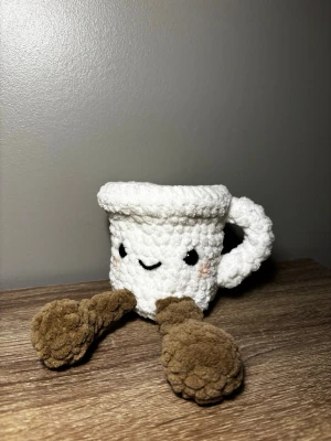 Virkad jellycat mugg - Söt handvirkad jellycat-mugg i vitt garn med bruna ben och ett gulligt broderat ansikte. Muggen har ett handtag och små rosa kinder, perfekt som dekoration eller present. Tillverkad i mjukt, fluffigt material.🫶🏻🫶🏻💞