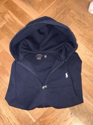 Mörkblå hoodie från Polo Ralph Lauren - Säljer en otroligt snygg hoddie från polo ralph lauren. Inga tecken på användning. Äkthetsbevis via qr koden. Och priset går absolut att diskutera. Hör av dig vid fler funderingar.