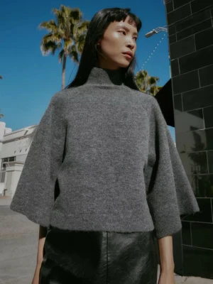 Helt ny Grå stickad polotröja med vida ärmar - Mysig grå stickad tröja med hög krage och vida trekvartsärmar. Tröjan har en boxig, avslappnad passform och är tillverkad i mjukt material som känns skönt mot huden. Perfekt för lager på lager och en chill look.