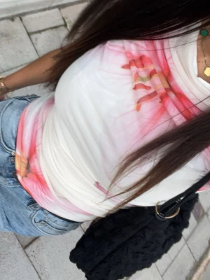Vit mesh topp med rosa mönster - Trendig vit mesh topp med rosa och orange abstrakt mönster. . Perfekt att styla med jeans eller kjol för en cool look.  Använt 2 gånger 
