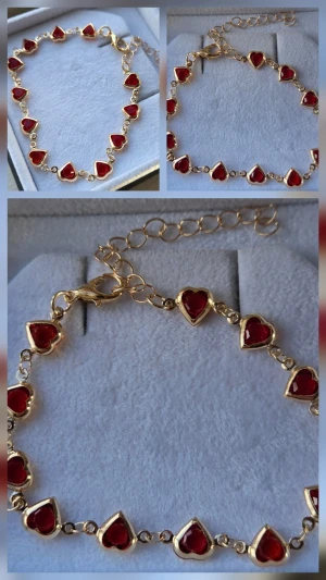 Guldarmband med röda hjärtan - Snyggt armband i guldfärgad metall med små röda hjärtan längs hela kedjan. Hjärtana har en glansig finish och armbandet har justerbar längd med karbinlås. Perfekt accessoar för att addera lite färg och kärlek till din stil.                     Detaljer: Färg: Guldton med klara röda hjärtan Huvudmaterial: Legering  Sten: Artificiell kristall (röd) Design: Länkarmband med hjärtformade stenar Längd: Ca 18 cm + 7 cm förlängningskedja Mått: 6 cm (i cirkel) Skick: Helt nytt / Oanvänt