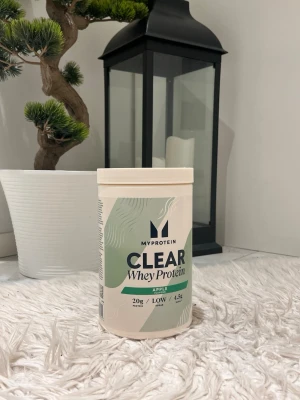 MyProtein Clear Whey Protein Äpple - ( MINDRE ÄN HALVA KVAR ) Säljer en burk MyProtein Clear Whey Protein med äppelsmak. Förpackningen är vit med gröna detaljer och tydlig text på framsidan. 