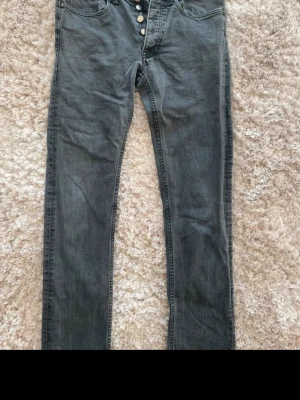 Gråa jeans Acne Studios - Säljer ett par gråa jeans med knappgylf. Jeansen har en lätt tvättad look och raka ben. Perfekta för en avslappnad och trendig stil. Materialet är mjukt denim som ger en skön känsla hela dagen. Från Acne studios