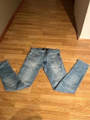 Ljusblå slim fit jeans från Replay  - Snygga ljusblå slim fit jeans från Replay med klassisk femficksmodell och diskreta slitningar. Jeansen har normal midja, dragkedjegylf och raka ben. Perfekta för en klassisk rik stil. 