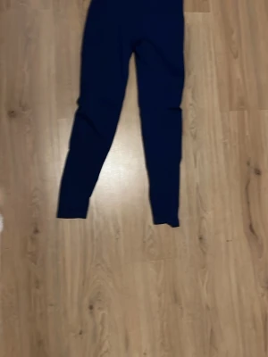 Mörkblå leggings från new yoker  - Snygga mörkblå leggings från STRONGER med hög midja och tight passform. Tillverkade i stretchigt material som passar perfekt för träning eller chill. Diskret logga i midjan och långa ben. Perfekta för dig som gillar stilrena träningskläder, även skrunch. Dom är nästan aldrig andvända och dom ser kort ut på bilden men dom är väldigt stretchiga jag som är 170 kan ha dom