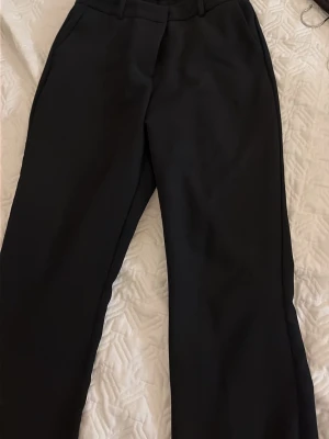 Svarta raka kostymbyxor från Bikbok - Snygga svarta kostymbyxor med raka ben och klassisk passform. Byxorna har hällor för skärp, sidofickor och en enkel bakficka. Perfekta till en stilren look och passar till många olika outfits.