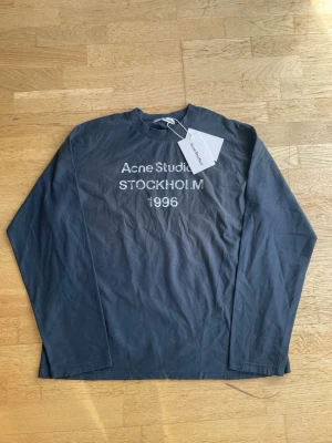 Acne Studios longsleeve  - Snygg mörkblå långärmad t-shirt från Acne Studios med tryck 'Acne Studios STOCKHOLM 1996' i vitt framtill. Klassisk rund hals och relaxed fit. Perfekt för dig som gillar stilrena plagg med streetkänsla.
