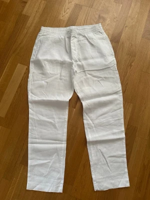 Vita linnebyxor från H&M Regular Fit - Snygga vita linnebyxor från H&M i regular fit. Byxorna har resår i midjan och sidfickor, vilket gör dem både bekväma och stilrena. Perfekta för en avslappnad och fräsch look under varma dagar.