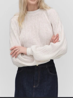 Vit ribbad topp från Stockh LM - Säljer en vit ribbad topp från Stockh LM med ballongärmar och hög hals. Toppen har en luftig och lätt struktur i ett mjukt material, perfekt för en trendig och avslappnad look. Passar snyggt till både jeans och kjol.