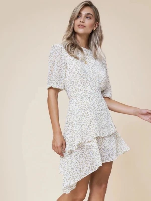 Adoore klänning  - Söt vit kortklänning från adoore med små gula blommor och volangdetaljer. Klänningen har puffiga korta ärmar och asymmetrisk nederkant som ger en trendig look. Perfekt för varma dagar och sommarens alla tillfällen. Strl 38 passar mig som vanligtvis har 36/s🌼