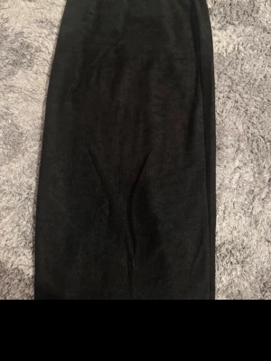 Svart långkjol från Gina Tricot - Säljer en svart långkjol från Gina Tricot. Kjolen har en enkel och stilren design med rak passform och resår i midjan. Perfekt att matcha med en crop top eller stickad tröja för en snygg look.