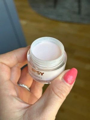 DIPSY Dip Powder ljusrosa - DIPSY Dip Powder i en mjuk ljusrosa nyans, perfekt för att skapa snygga och hållbara naglar. Kommer i en stilren glasburk med guldfärgat lock. Pulvret ger en naturlig och fräsch look och är lätt att applicera för ett proffsigt resultat.