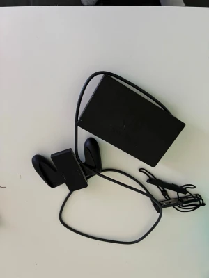 Nintendo Switch med tillbehör - Nintendo Switch spelkonsol med neonröda och blå Joy-Con-kontroller, svart dockningsstation och laddkabel. Konsolen har en rektangulär form med stor skärm och avtagbara handkontroller. Perfekt för gaming både hemma och på språng.