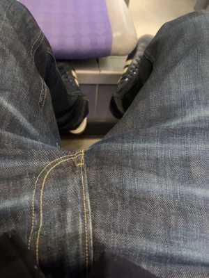 Replay blå jeans med slitningar - Säljer ett par snygga blå jeans från Replay med klassisk femficksmodell och coola slitningar på bakfickan. Jeansen har kontrastsömmar och en patch med Replay-logga bak i midjan. Perfekta för dig som gillar en avslappnad och trendig stil.