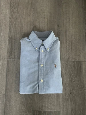 Ralph Lauren skjorta - Säljer nu en ljusblå Ralph Lauren skjorta i storlek Xs. Den är i mycket bra skick och har inga defekter. Stilren skjorta som är enkel att matcha med ett par jeans eller ett par linnebyxor nu till sommaren. Hör av dig vid minsta fundering🤩 Obs! Måtten fick inte plats i bilderna men de är 66cm från toppen till botten och 45 rakt över mätt precis under första knapp.