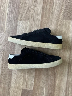 Saint Laurent SL/06 - Säljer ett par svarta saint Laurent sneakers i modell SL/07. Skorna är i mocka och storleken är 41,5 eu. Endast skor medföljer vid köp. Kom pm för fler frågor eller bilder 🫡