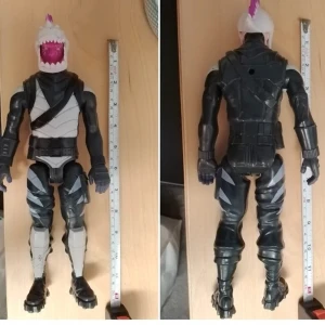 Stor Fortnite actionfigur Shark - Säljer en stor Fortnite actionfigur med hajhuvud och rosa tagg på toppen. Figuren har svarta, grå och vita detaljer, rustningsliknande kläder och coola boots. Perfekt för samlare eller som dekoration i gamingrummet.