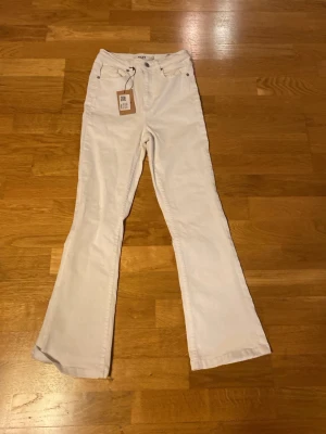 Vita bootcut jeans från NA-KD - Snygga vita bootcut jeans från NA-KD med klassisk femficksmodell och hög midja. Jeansen har vida ben och är tillverkade i ett mjukt bomullsmaterial med lite stretch för extra komfort. Perfekta för en trendig och avslappnad look.