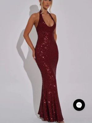 ODETTE MAXI DRESS - WINE  - Säljer en vinröd långklänning med glittriga paljetter och djup urringning. Klänningen har smala axelband och figurnära passform som framhäver siluetten. Perfekt för dig som vill sticka ut på bal eller fest! Aldrig använd då den va för liten vid brösten! Funkade inte att göra retur via babyboo så säljer jag den här. Stl XS 