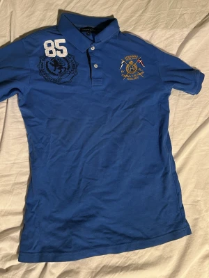 Blå piké från Tommy Hilfiger - Säljer denna blåa piké från Tommy Hilfiger i storlek XL i barnstorlek vilket motsvarar ca storlek 176.