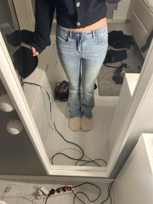 Ljusblå bootcut jeans - Säljer ett par ljusblå bootcut jeans med klassisk femficksdesign och normalhög midja. Jeansen har en lätt tvättad look och är i stretchigt denimtyg som sitter snyggt över höfterna och låren innan de blir vidare nertill.