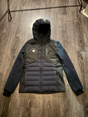 Mörkblå dunjacka från Sail Racing - Tja! Säljer en  mörkblå dunjacka från Sail Racing med huva och dragkedja. Säljer den då den är för liten för mig. Storleken är XS, det är en snygg jacka som är perfekt för kalla vinterdagar. Jackan är i ett mycket fint skick, inga defekter osv, 