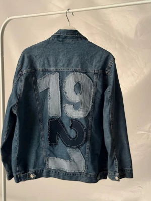  Jeansjacka med patchad rygg - Oversized blå jeansjacka med stora patchade siffror. Perfekt för dig som gillar streetwear och unika detaljer.🩵