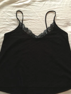 Svart spetslinne från Zara - Snygg svart linnetopp med tunna axelband och v-ringning dekorerad med spets från Zara. Jätte fin, perfekt till sommaren. 